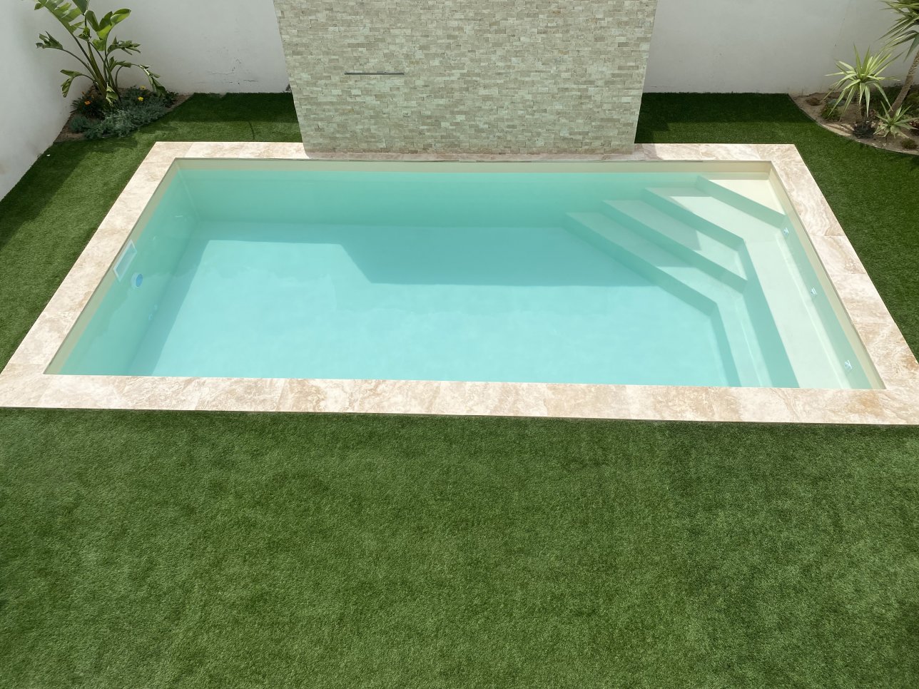 piscine beige avec l'escaliers dans l'angle